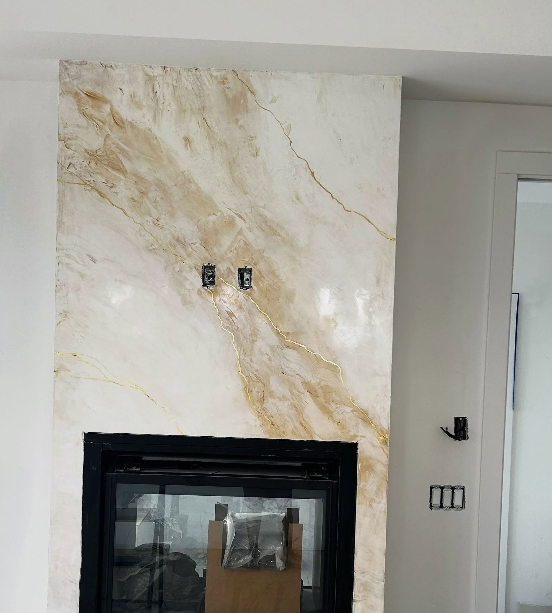 Fireplace chimney breast finished in cream marble Venetian plaster with gold veining