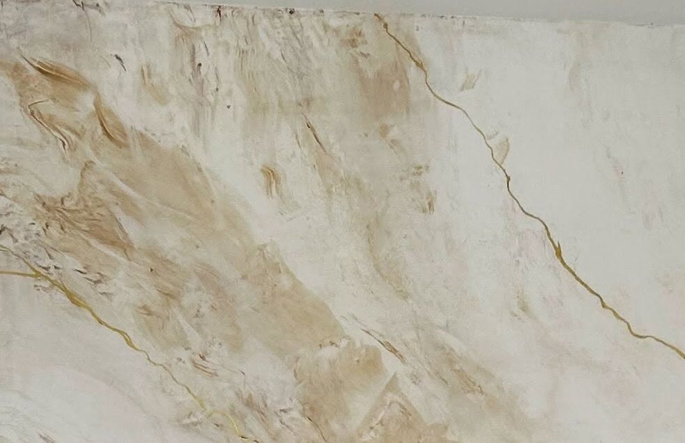 Close-up of hand-applied marble Venetian plaster with soft ochre clouding and fine gold veins